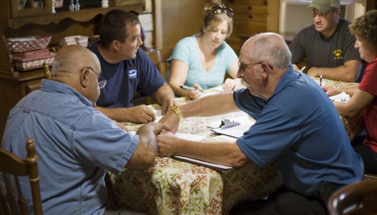 A group of people sitting around a kitchen table.