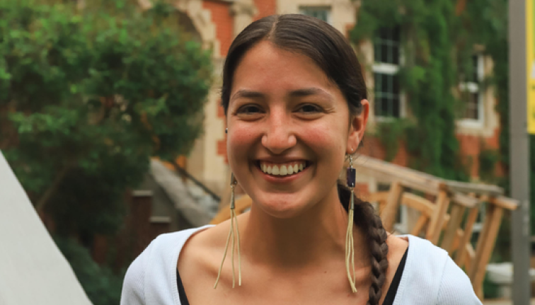 A photo of Cheyenne in a white shirt in front of a building.