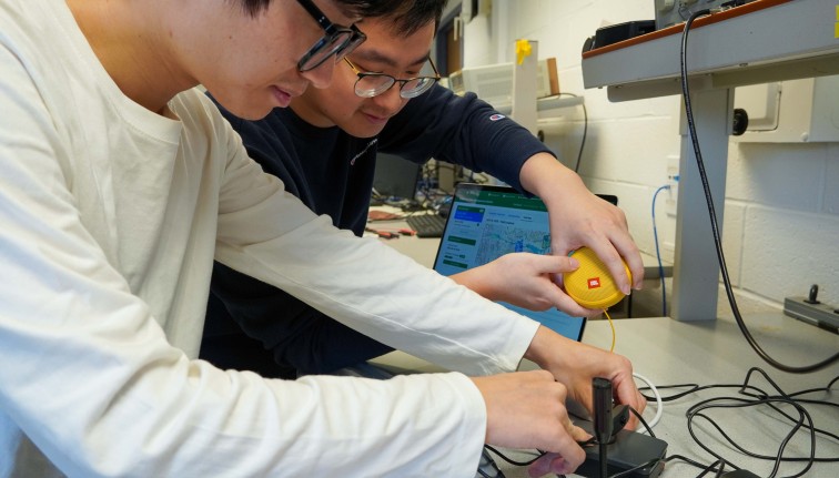 two men work on a piece of tech in a lab