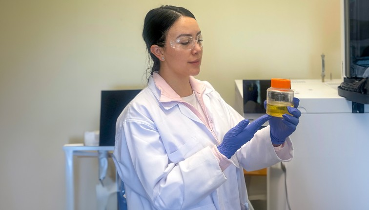 a woman in a lab coat looks at a beaker of liquid