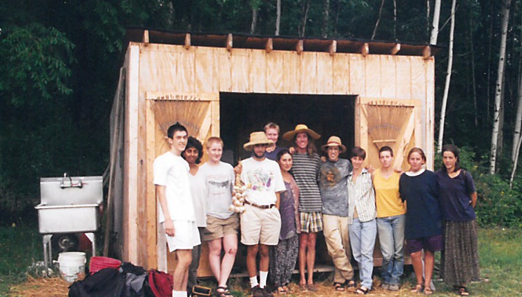 A group of people in front of the construction site of a small shed 