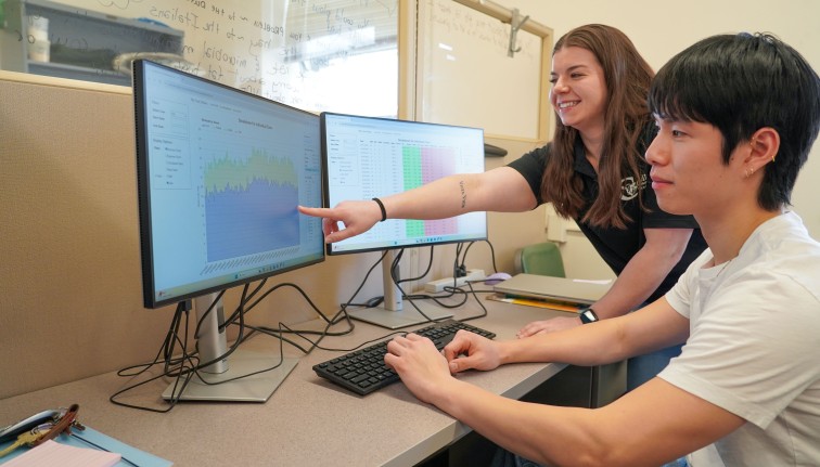a woman points out data on a screen to a man