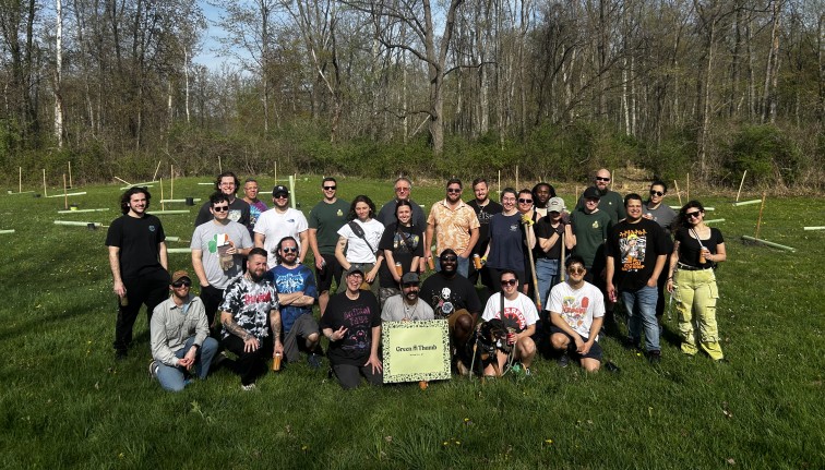 Photograph of a group of people posed in a field with a woodland behind them.