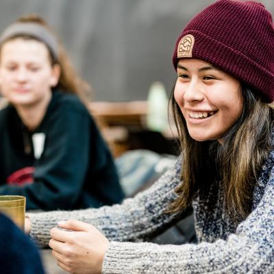 A girl wearing a hat sits at a table and laughs