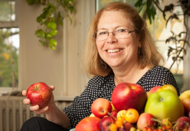 Smiling woman holds apple.