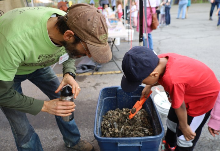 Two people look at a vermicompost box