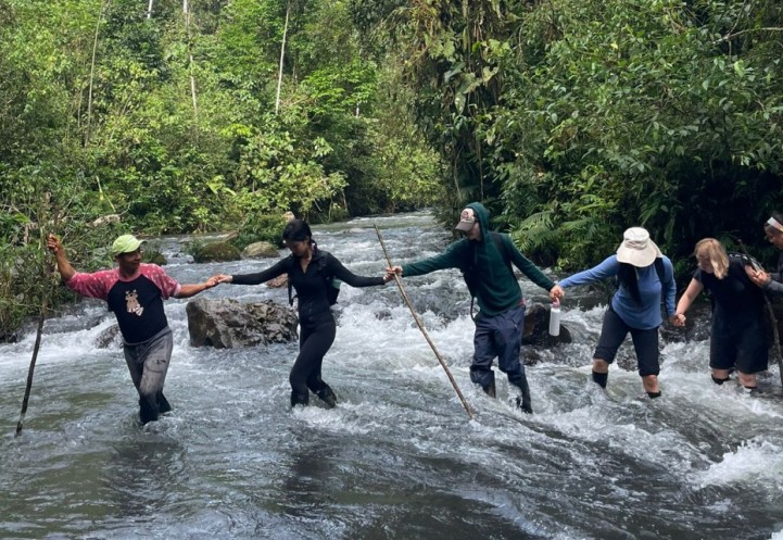 Students holding hands crossing a creek