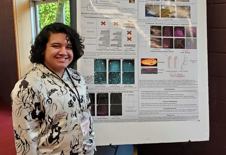 Students stands next to poster presentation.