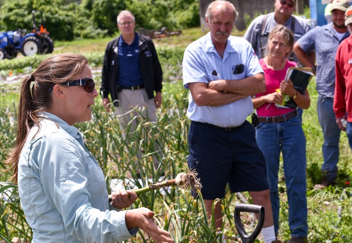 Crystal Stewart Courtens at CCE field day holding garlic and speaking to attendees