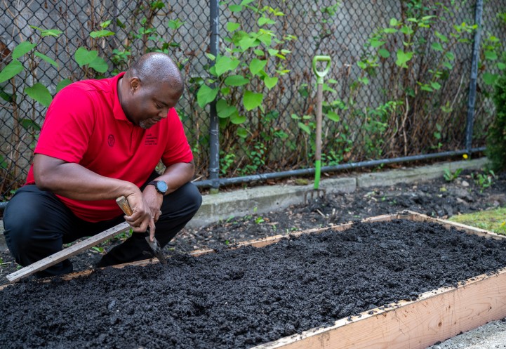 Kwesi Joseph at a raised bed, holding a trowel