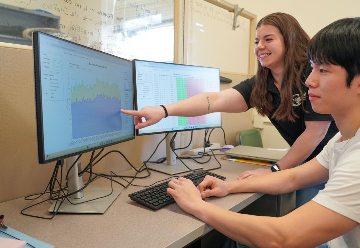 a woman points out data on a screen to a man