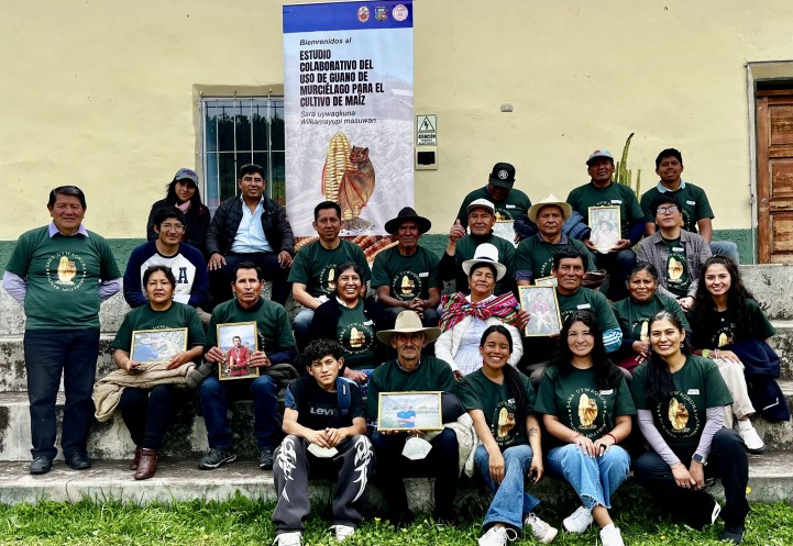 group of individuals smile for a picture in front of maize banner