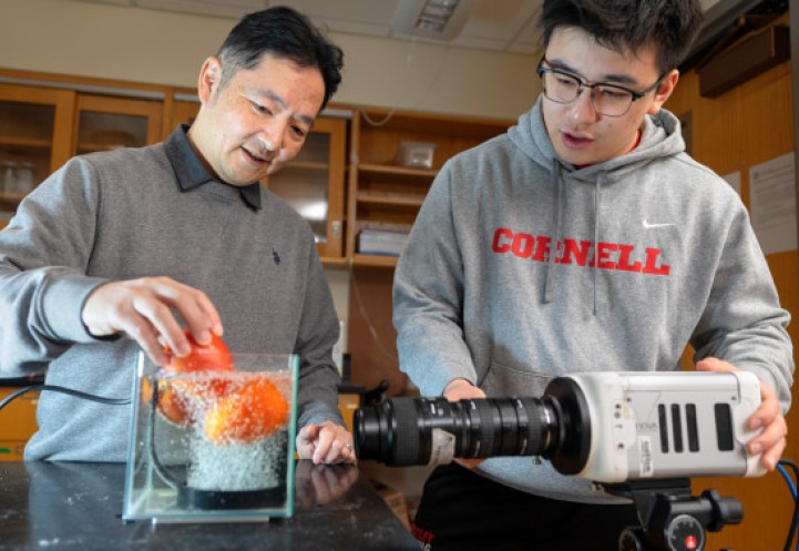 Sunny Jung (left) places a tomato in a prototype bubbler for cleaning produce while Yany Lin films the experiment with a camera.