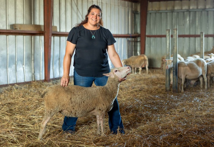 a woman holds a sheep in a show stance