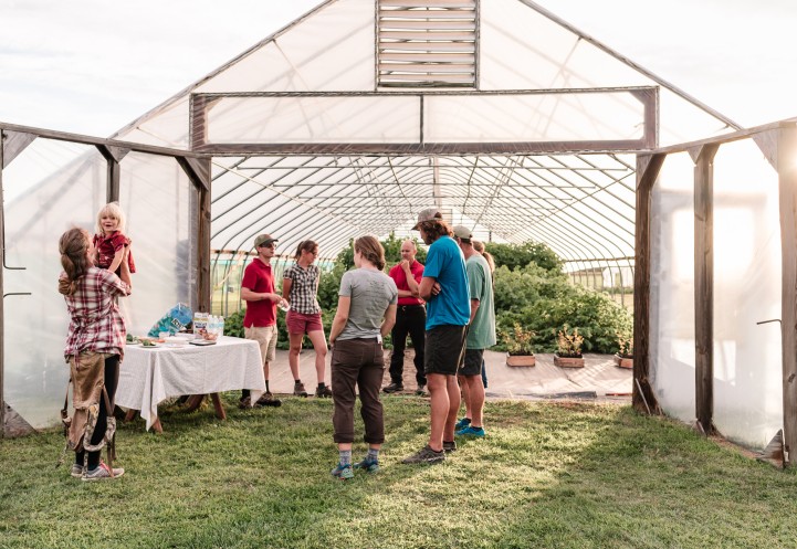 a group of people in front of a high tunnel with crops