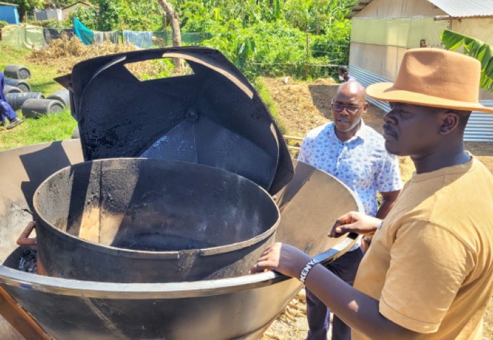 Charles Midega (left) and Roy Odawa display the Kontiki kiln they modified to make biochar from human feces. Credit: Rebecca Nelson