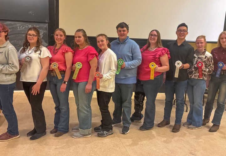 a croup of teenagers stand in a line holding ribbon awards