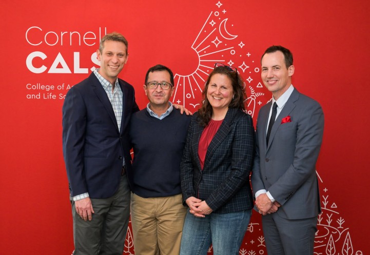 four people stand in front of a red background with the CALS logo on it