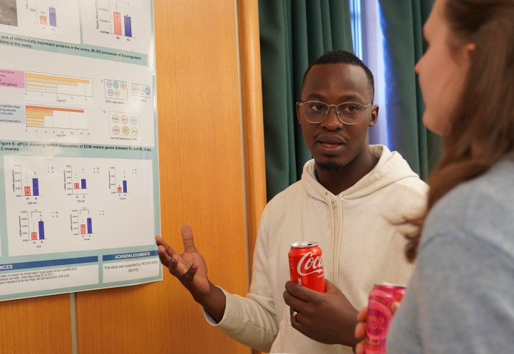 a man gestures at a poster on the wall as he talks to a woman