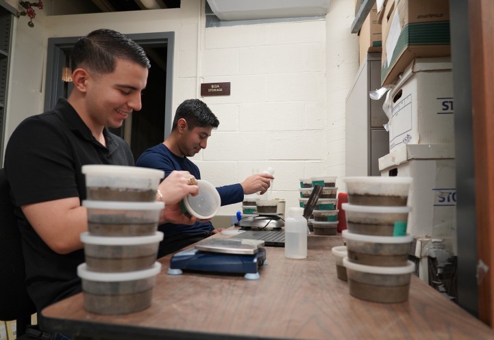 Two people work with scientific equipment on a desk.
