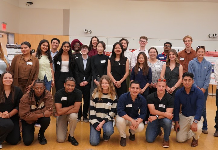 A group of people stand in two lines, each individual posing for the group photo.