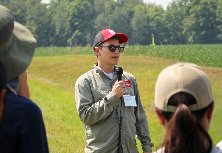 Louis Longchamps speaking to a group of people at a farm