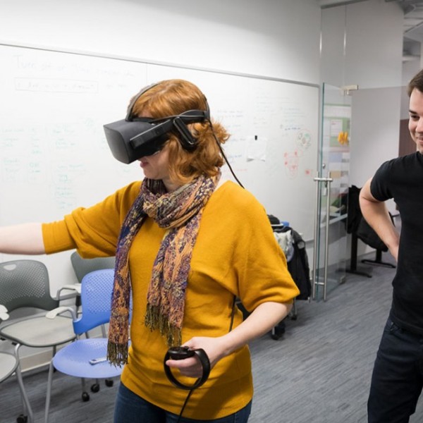 Jack Madden watches as Andrea Stevenson Won uses a virtual reality simulator