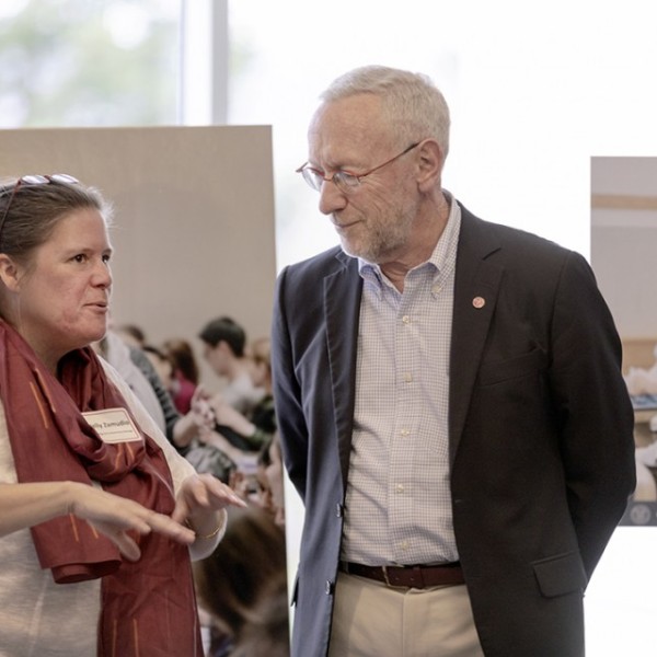 Kelly Zamudio and Provost Michael Kotlikoff talk in front of images on easels