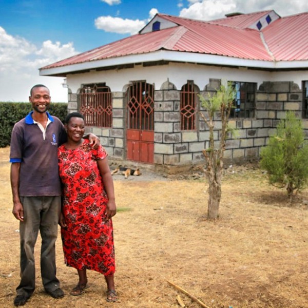 Farmers stand outside their house