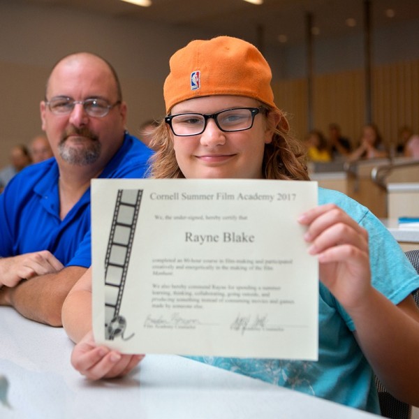 middle school student holds up certificate with father