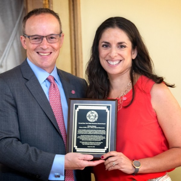 Joel Malina and Christa Glazier stand, smiling, and holding a plaque