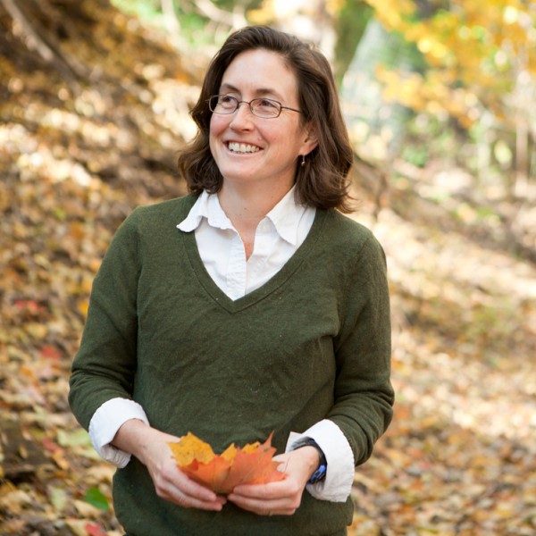natalie mahowald stands in a forest holding leafs