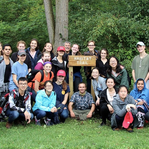 students sit around a sign that says "habitat trail"