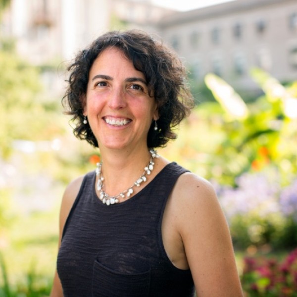 A woman stands in a garden and smiles