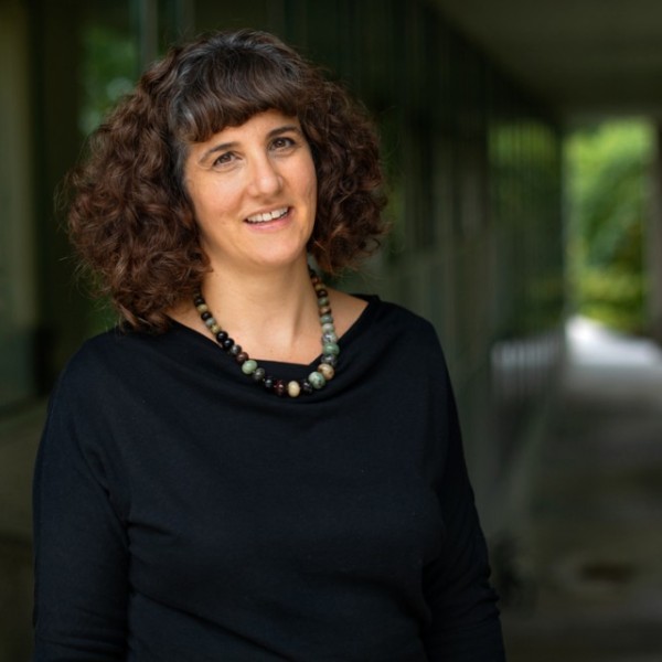 Female professor stands in outdoor archway 