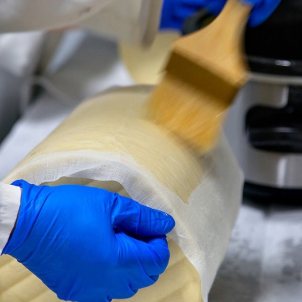 Gloved hands wrap cheese in wax paper