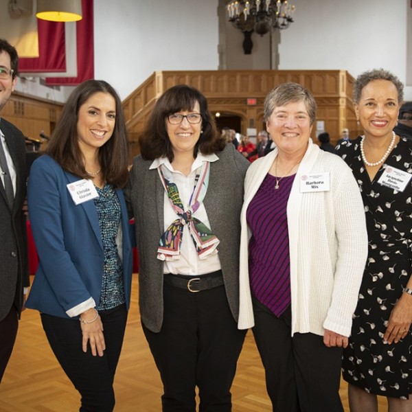 A group of adults, containing two men and four women, standing together in a line smiling for the camera