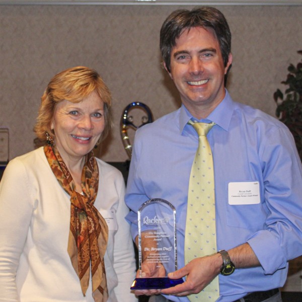 A woman stands next to a man holding an award