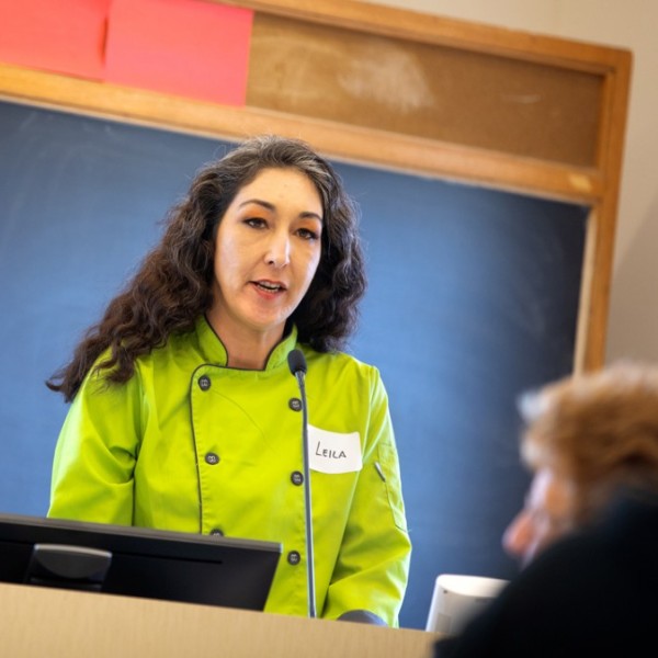 A woman standing at a podium in a green shirt talking to an audience