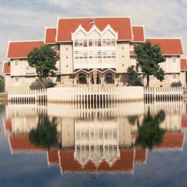 A large building near a lake reflects onto the still lake