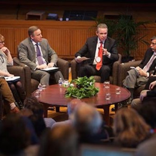 Seven people sit around a table and talk