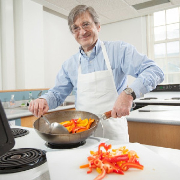 A man cooks peppers in a pan on the stove