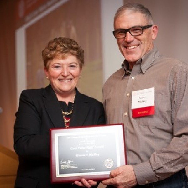 A woman and man stand together holding an award