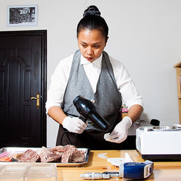 A woman holds a blowdryer in one hand while making chocolate