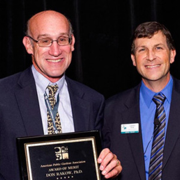 Two men stand together and hold an award
