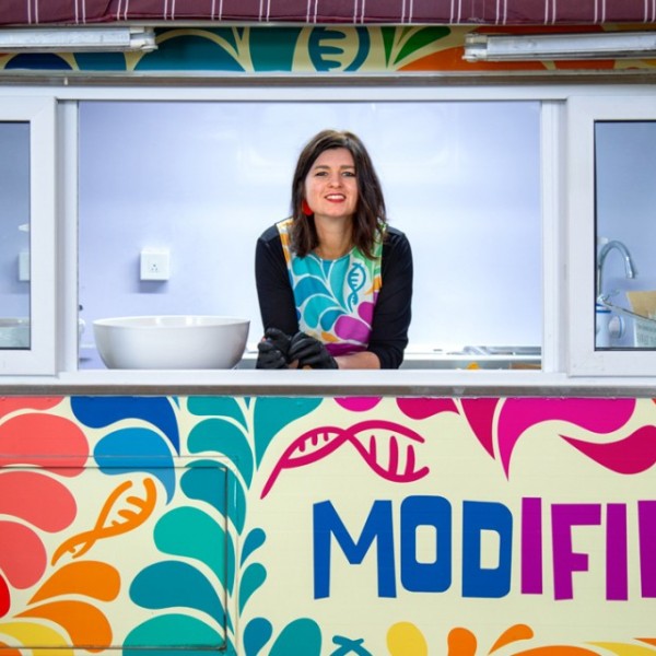 A woman standing and looking out a window of a colorful food truck