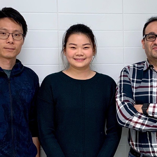 Two men stand on either sides of a women