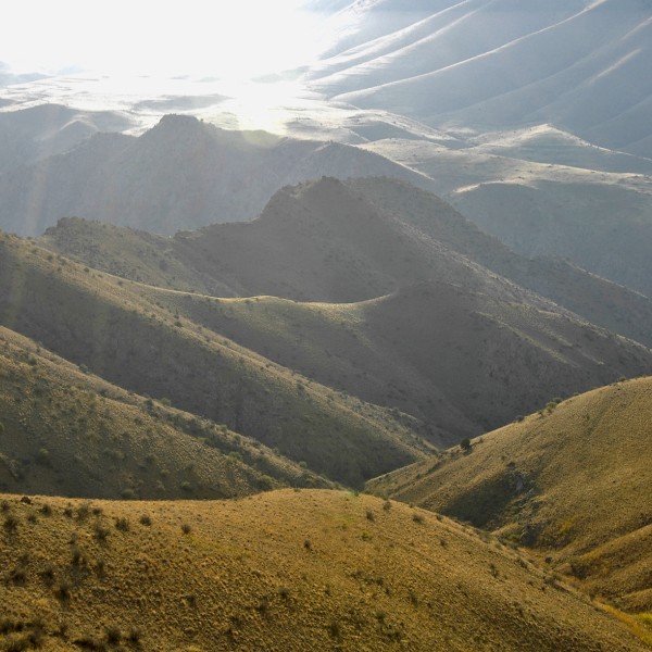 The sun shines down upon rolling mountains on the Armenian countryside