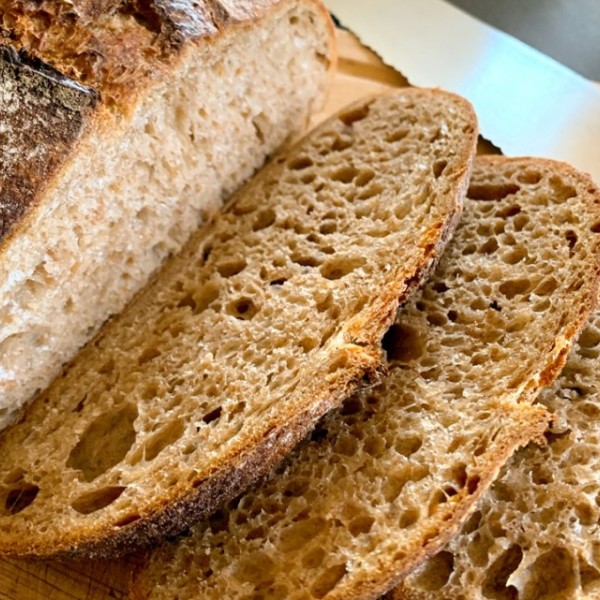 A loaf of bread sits cut on a wooden board