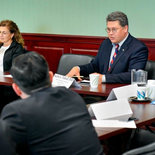 A group of legislators and other government workers discuss in a legislation room